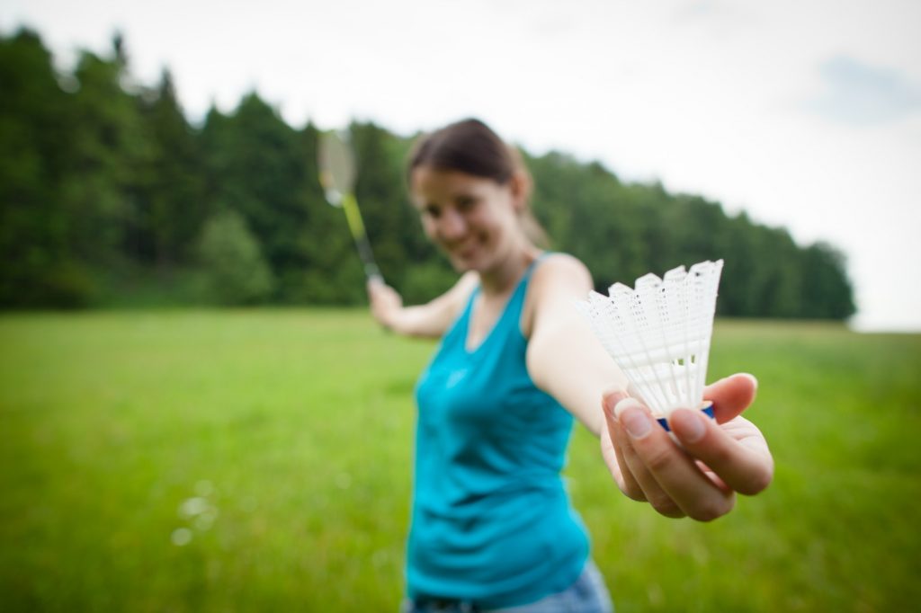 Pretty, young woman playing badminton in a city park on a lovely